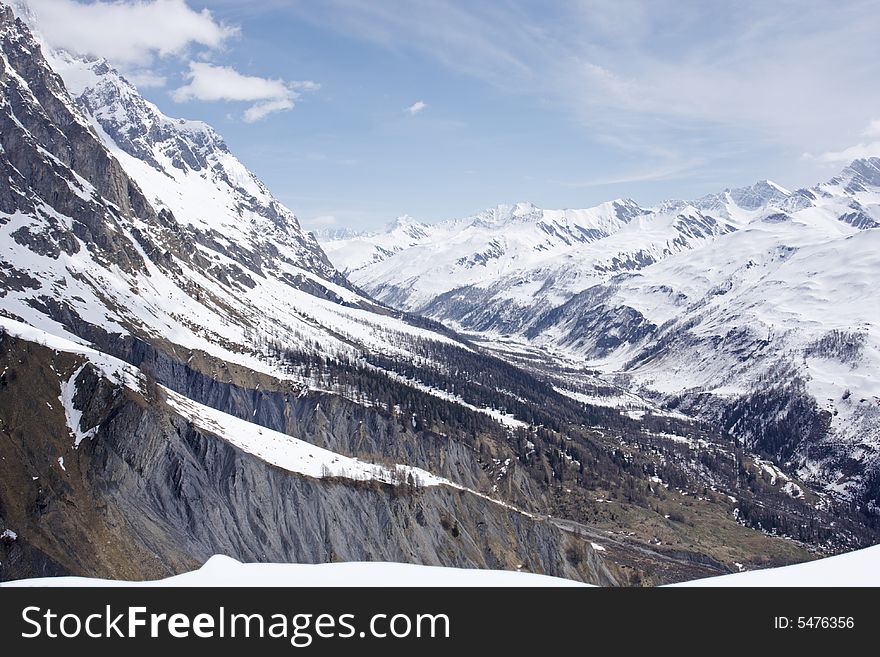 An alpine valley above Courmayeur in Val D'Aosta, Italy. It is in early spring and the snow is melting on the lower slopes. An alpine valley above Courmayeur in Val D'Aosta, Italy. It is in early spring and the snow is melting on the lower slopes.