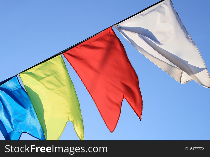 Red, yellow, blue and white flags flapping on wind. Red, yellow, blue and white flags flapping on wind.