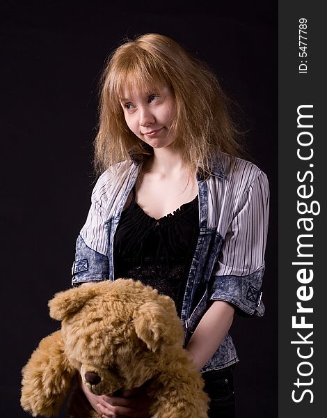 Blonde girl on black handing teddy bear. Blonde girl on black handing teddy bear