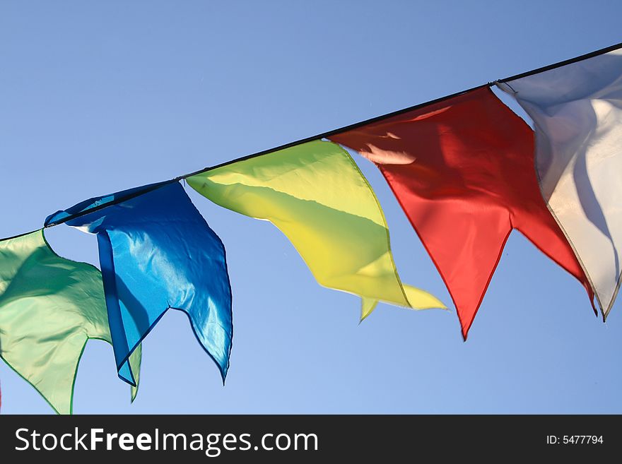 Red, yellow, blue, green and white flags flapping on wind. Red, yellow, blue, green and white flags flapping on wind.