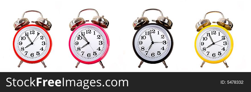 Several brightly colored traditional alarm clocks thrown on a white background