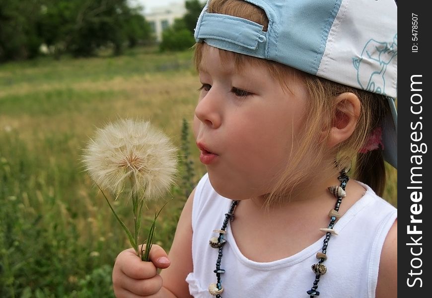 Little girl blowing dandelion seeds