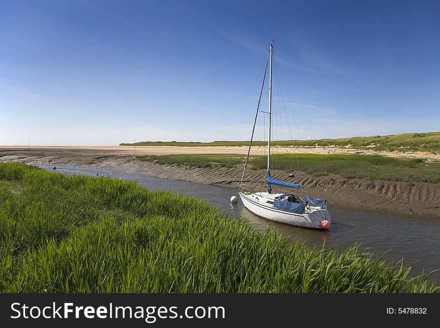 Yacht moored in river adjacent to sand dunes. Yacht moored in river adjacent to sand dunes