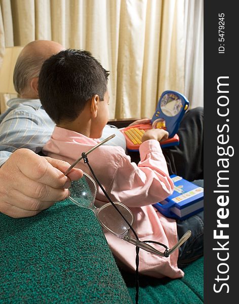 Grandfather And Grandson Sitting On Couch Playing