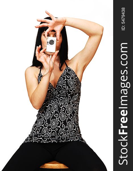 An young pretty girl in a black and white dress sitting on a chair and taking pictures in an studio for white background. An young pretty girl in a black and white dress sitting on a chair and taking pictures in an studio for white background.