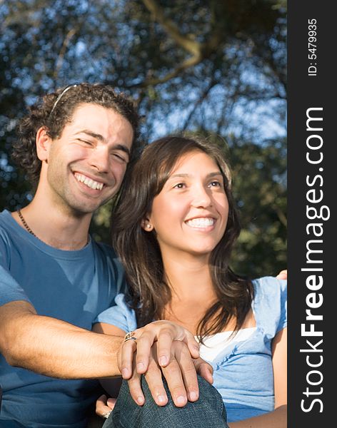 Close up picture of a happy couple sitting together outside. Vertically framed photograph. Close up picture of a happy couple sitting together outside. Vertically framed photograph