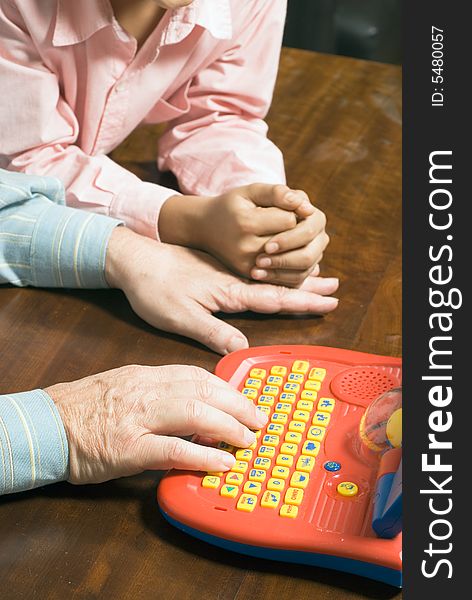 Close-up of grandfather and grandsons hands close to the toy. Grandfather is typing on the toy as grandson watches next to him. This is a vertically framed photo. Close-up of grandfather and grandsons hands close to the toy. Grandfather is typing on the toy as grandson watches next to him. This is a vertically framed photo.