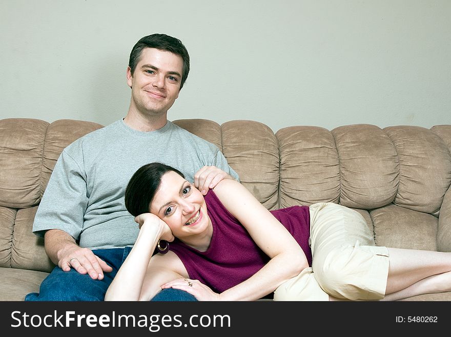 A smiling woman lying on a smiling man's lap sitting on a sofa. A smiling woman lying on a smiling man's lap sitting on a sofa.