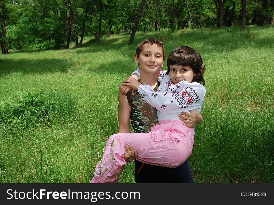 Boy hold girl in arms over green grass