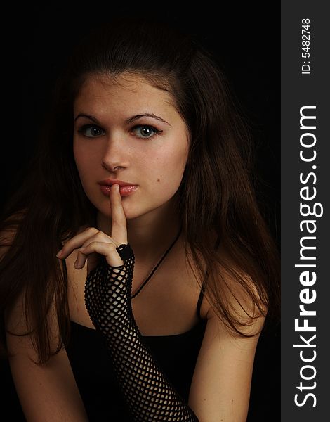 Young girl in black dress with a finger near the lips. Young girl in black dress with a finger near the lips