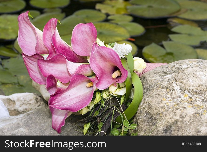 Beautiful bridal bouquet lying by the garden pond. Beautiful bridal bouquet lying by the garden pond.