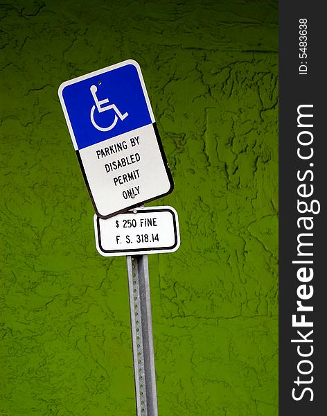 disabled parking sign in front of a green textured wall (sRGB). disabled parking sign in front of a green textured wall (sRGB)