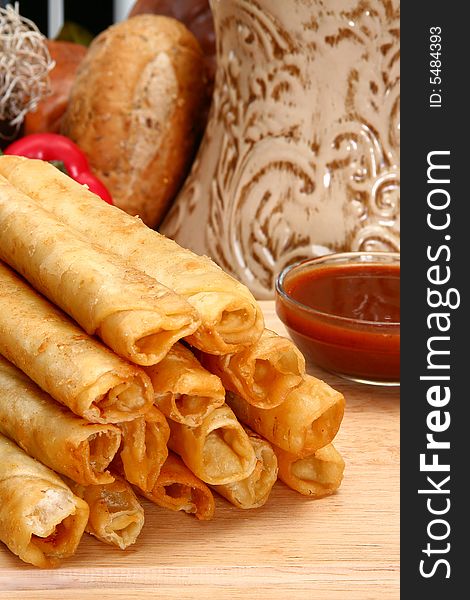 Stack of chicken taquitos with hot sauce and sour cream in kitchen or restaurant