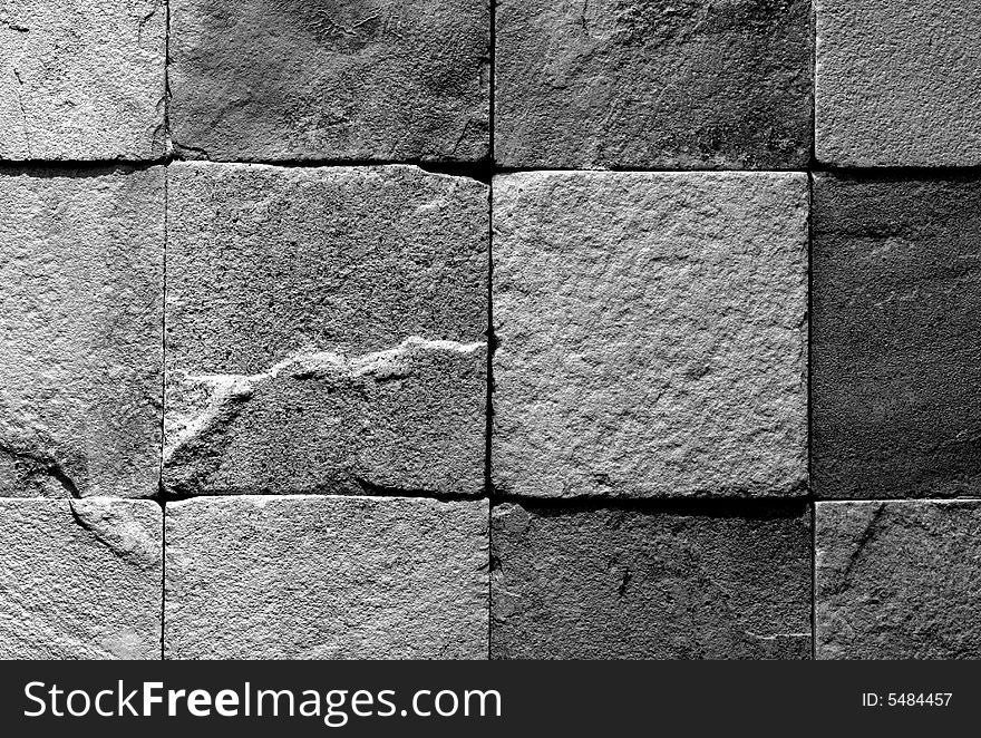 Black and white image of a section of wall made of roughly finished tiles. Black and white image of a section of wall made of roughly finished tiles