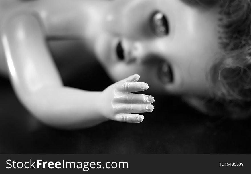 A black and white portrait of a broken doll with focus on the hand. A black and white portrait of a broken doll with focus on the hand