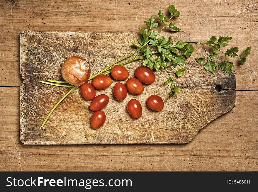 Tomato, parsley and onion on wooden table.