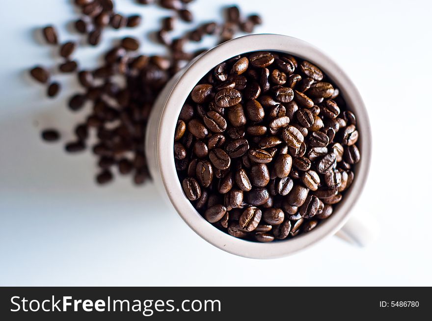 Whole bean coffee in mug isolated on white with beans scattered around mug