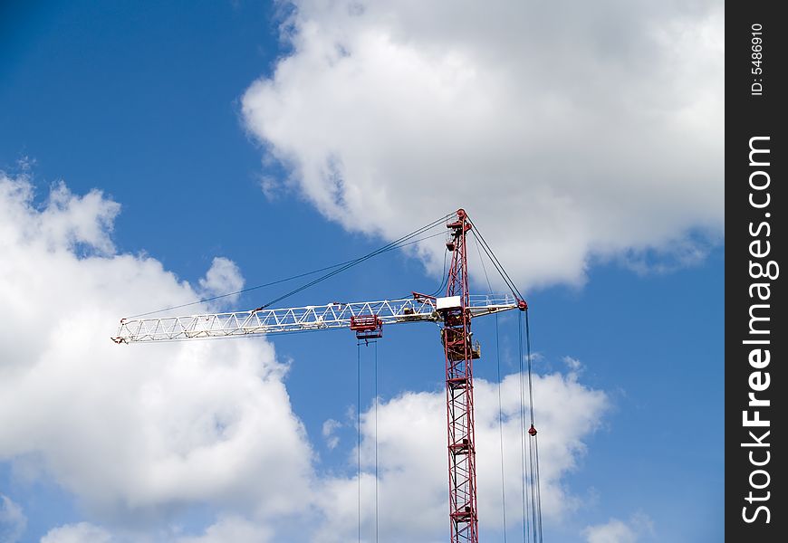 The elevating crane and blue sky with clouds