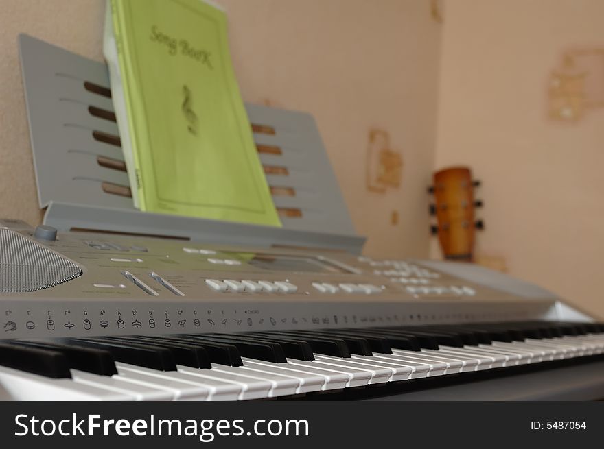 Photo of electric synthesizer and guitar neck in a room corner. Photo of electric synthesizer and guitar neck in a room corner