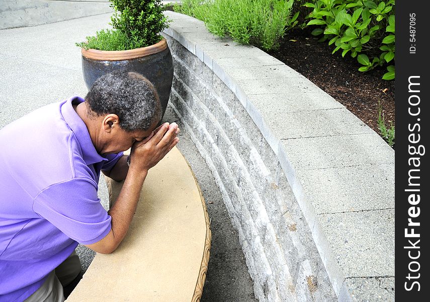 Muslim man praying outside on the ground.
