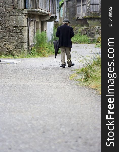 Old man with an umbrella strolling along a village path. Old man with an umbrella strolling along a village path