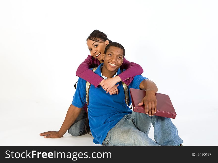 Two seated students laugh at the camera while she has her arms around his neck. Horizontally framed photograph. Two seated students laugh at the camera while she has her arms around his neck. Horizontally framed photograph