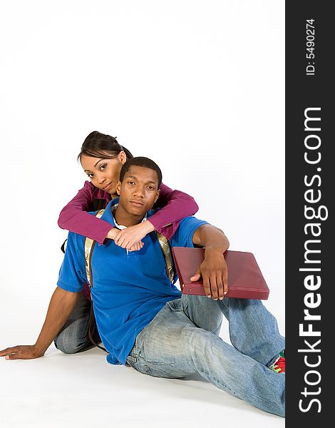 Two seated students look at the camera while she has her arms around his neck. Vertically framed photograph. Two seated students look at the camera while she has her arms around his neck. Vertically framed photograph