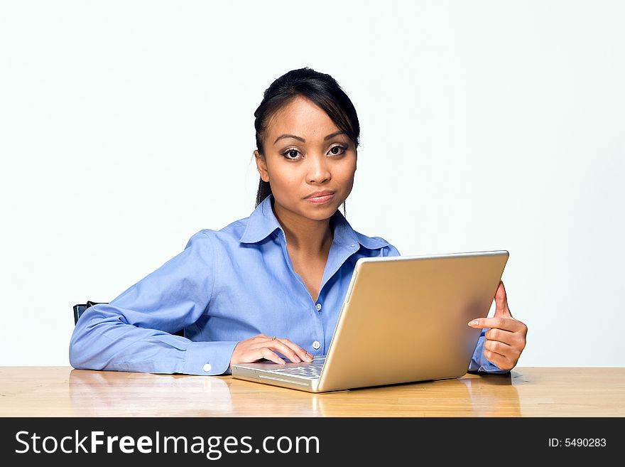 Female student working on her laptop appears bored while looking at the camera. Horizontally framed photograph. Female student working on her laptop appears bored while looking at the camera. Horizontally framed photograph