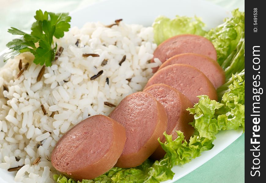 Sliced sausage with rice and salad
