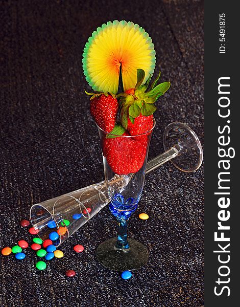 Composition made with Champagne glass full of strawberries and colorful chocolate drops. Composition made with Champagne glass full of strawberries and colorful chocolate drops