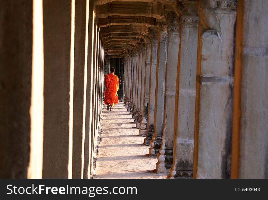 A monk walking through an ancient hall. A monk walking through an ancient hall.
