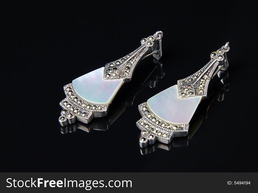 Earrings with mother of pearl and marcasita stones over black background