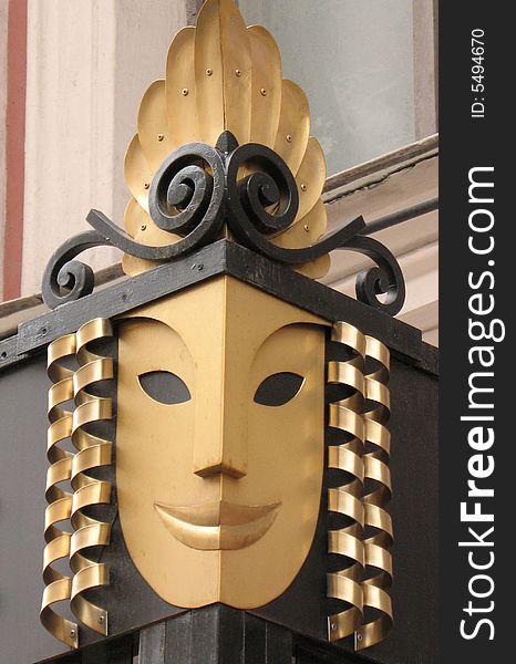 A conventionalized mask on the corner of the roof of porch in the little theatre.