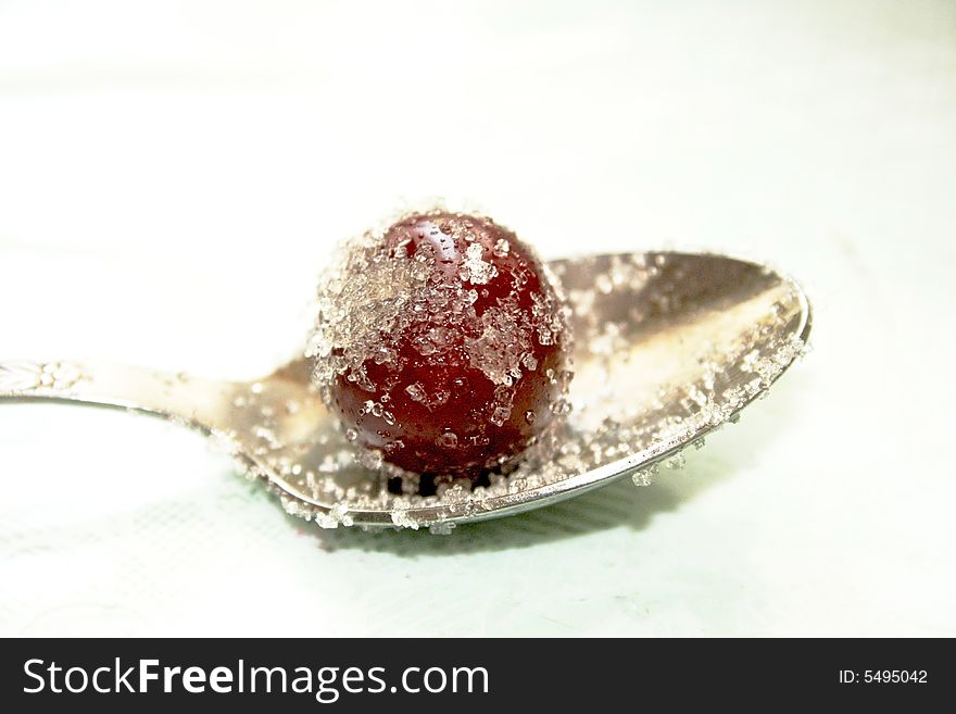 Cherry in sugar on a spoon. Cherry in sugar on a spoon