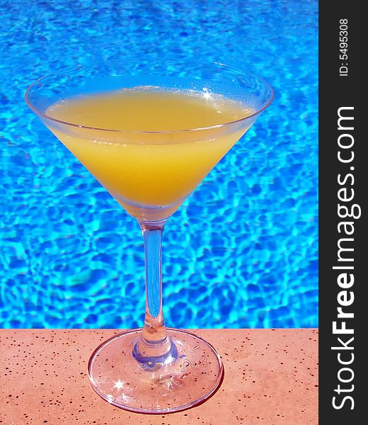 Glass of orange juice on pool edge. Glass of orange juice on pool edge