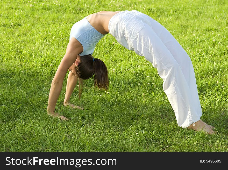 Sporty girl exercising on meadow against the sky