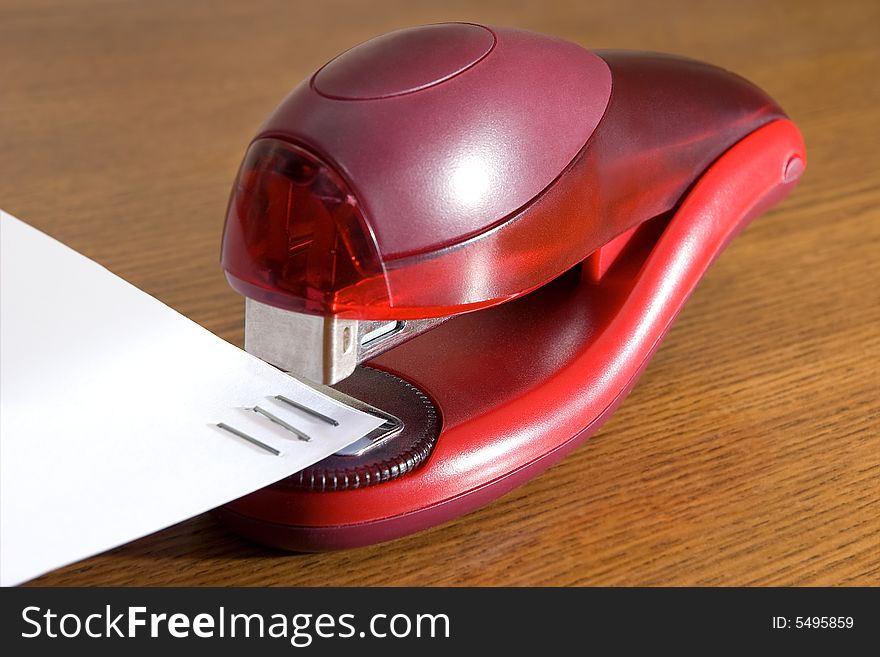 Stapler of red color on a brown table