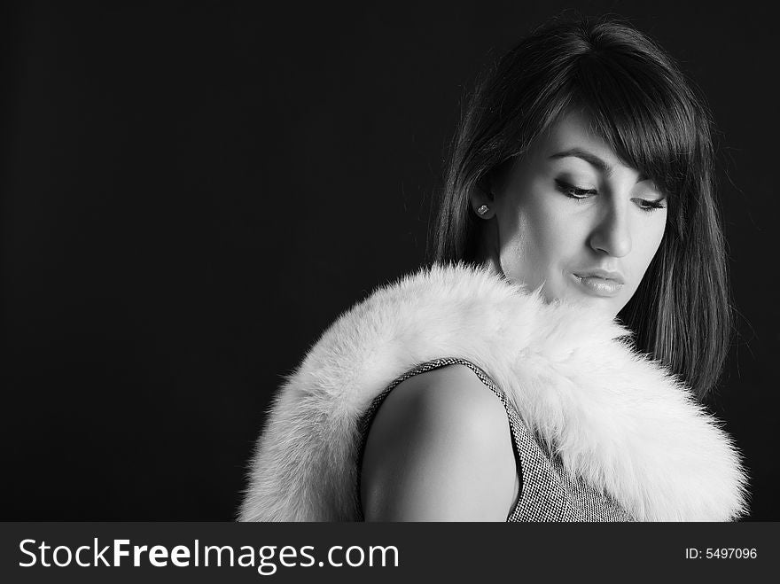 Young girl in grey clothes with a collar from white fur on a black background. Young girl in grey clothes with a collar from white fur on a black background