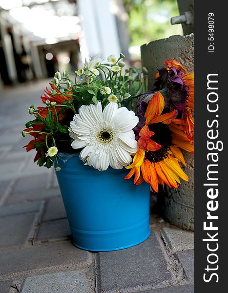 An image of a floral arrangement in a bright blue tin. An image of a floral arrangement in a bright blue tin