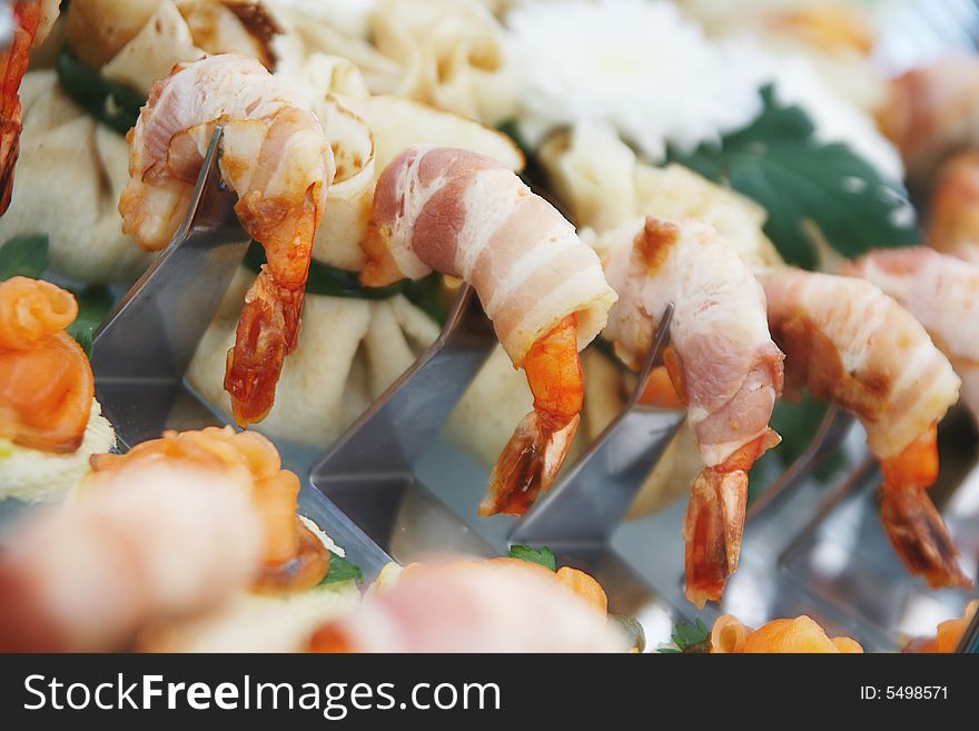 Prawns are wrapped in bacon and are sitting on serving table decorated with flowers. Prawns are wrapped in bacon and are sitting on serving table decorated with flowers