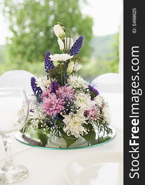 Flowers arranged in composition are standing on white dining table. Flowers arranged in composition are standing on white dining table