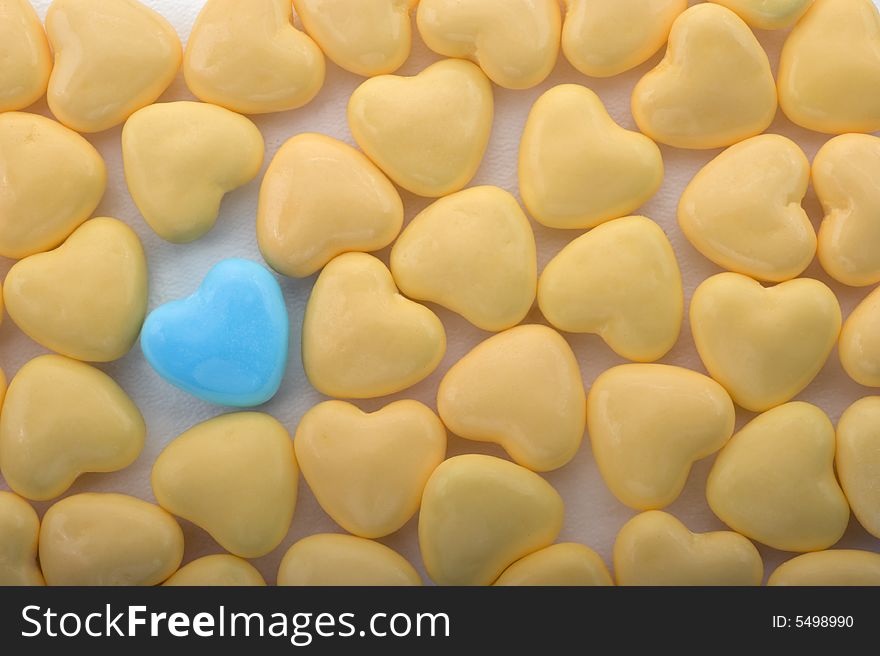 Heart shaped yellow with one blue candy candies background
