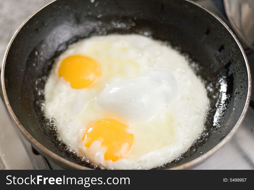A pair of fried eggs over in a pan. A pair of fried eggs over in a pan.