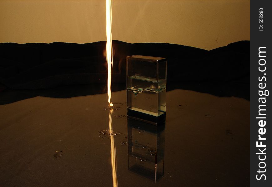 Burning candle drop beside standing object on glass background. Burning candle drop beside standing object on glass background