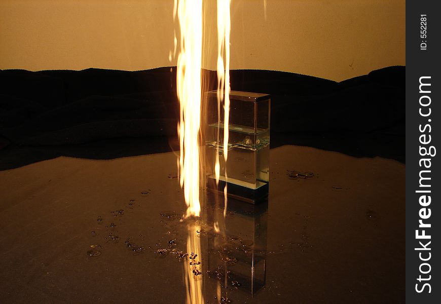 Burning candle drops beside object like sand clock. Burning candle drops beside object like sand clock