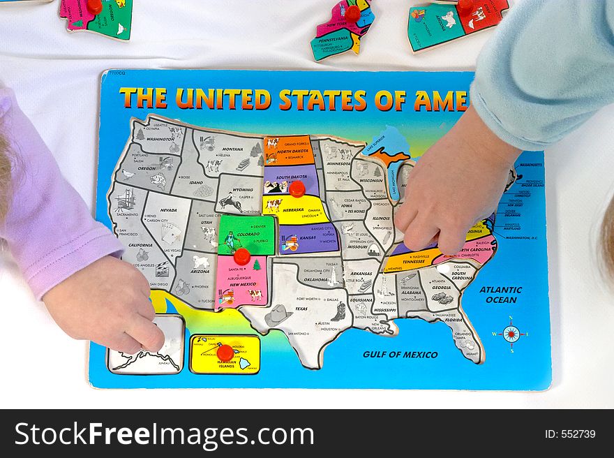 Two children putting together a wooden puzzle of the United States. Two children putting together a wooden puzzle of the United States