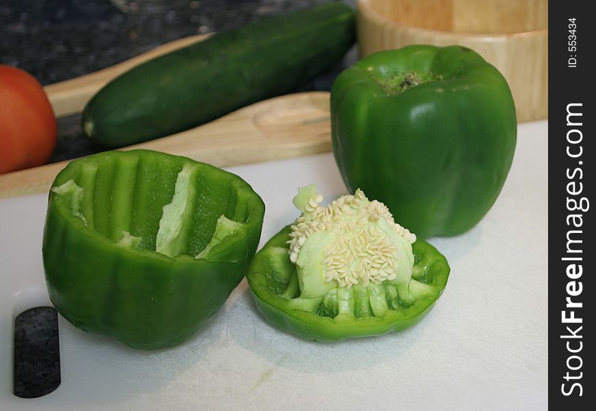 Green bell peppers on a cutting board, being cut. Green bell peppers on a cutting board, being cut