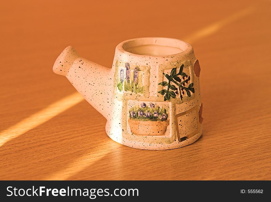 Clay candle support in evengning light on a wood table