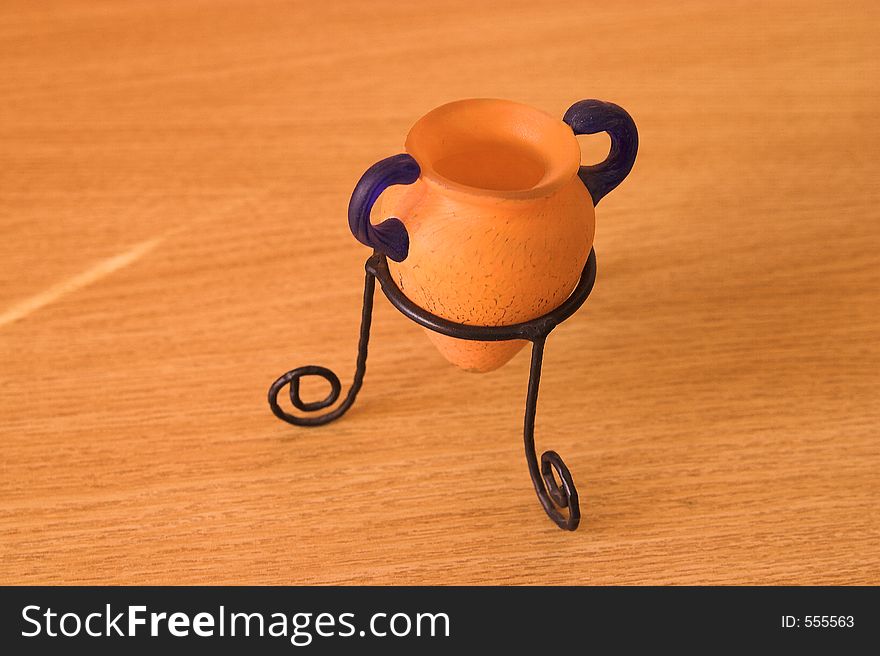 Greek vase birds eye view syle with blue and orange colors in a metal support on wood table