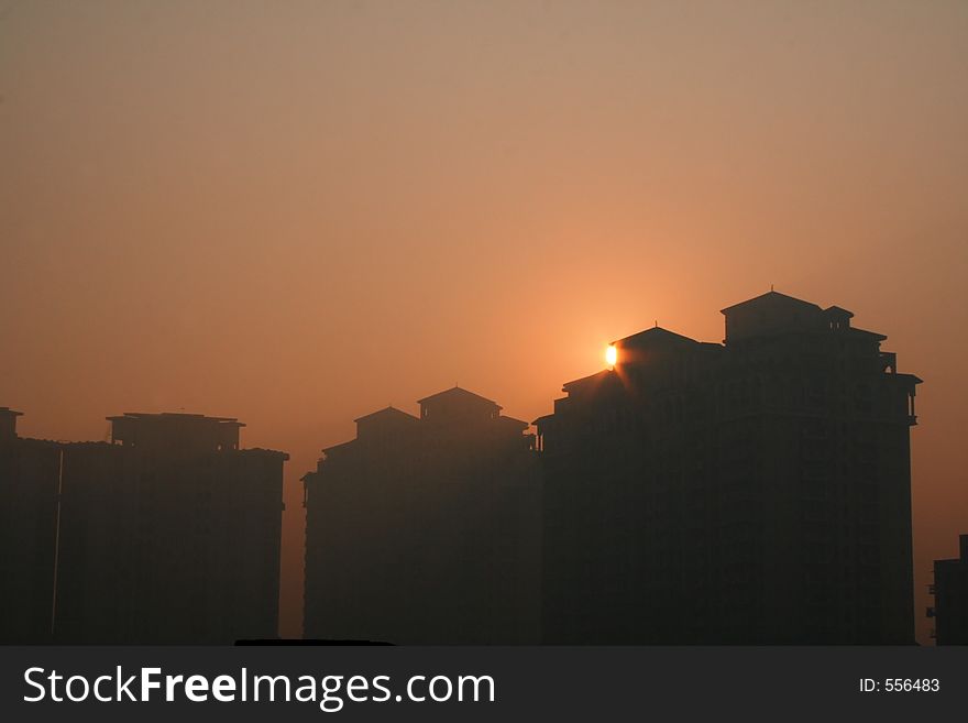 Sunsets behind a skyscraper high rise building eclipsing it in Gurgaon India. Sunsets behind a skyscraper high rise building eclipsing it in Gurgaon India